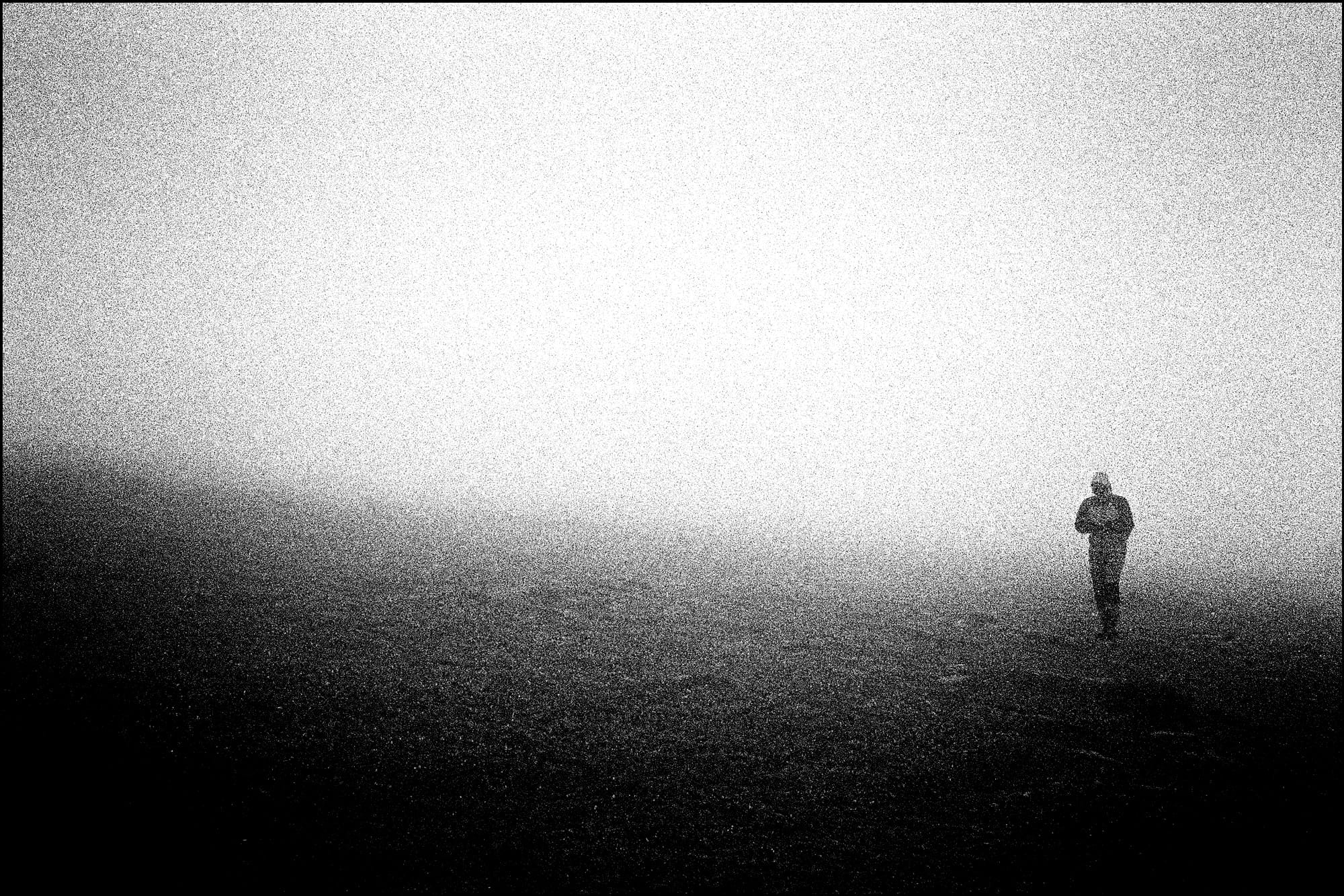 Un uomo cammina avvolto nella nebbia a Capo Nord, in Norvegia. Fotografia in bianco e nero
