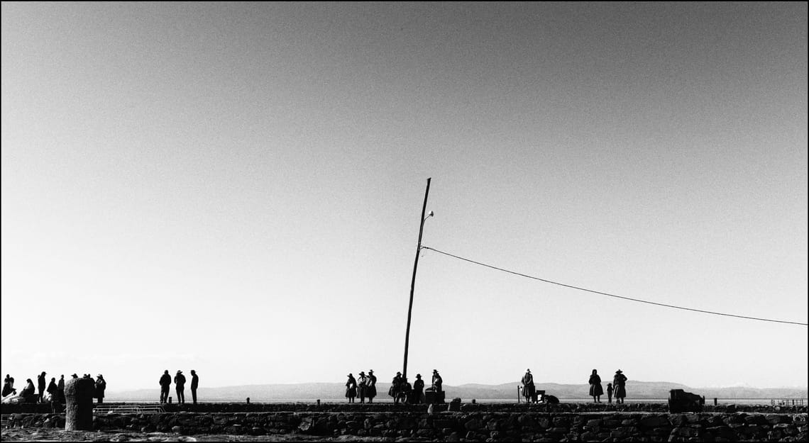 Un gruppo di persone aspetta l'imbarco al porto di Taquile. Fotografia in bianco e nero.