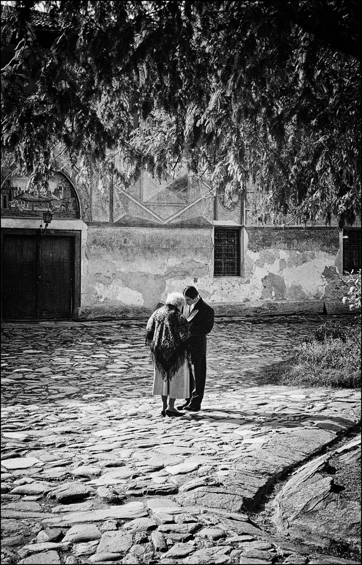 Due persone si scambiano qualcosa. Fotografia in bianco e nero.