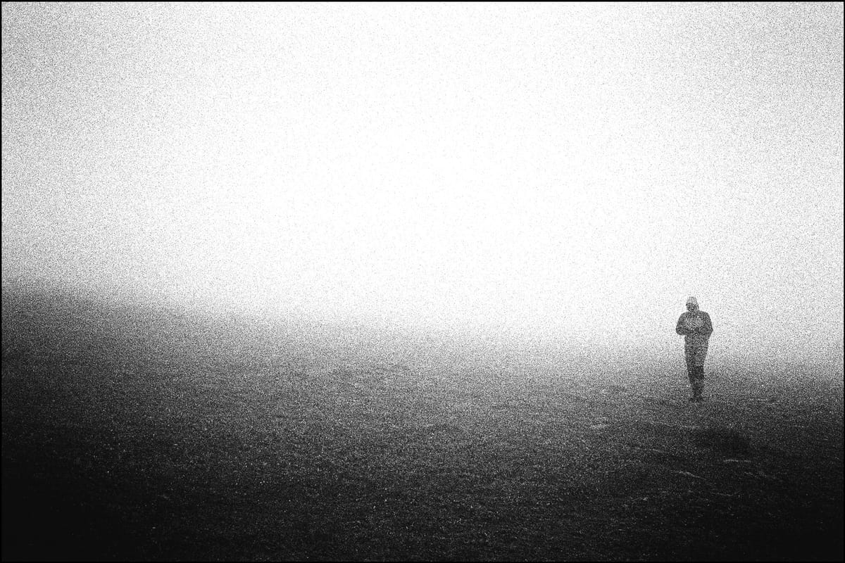 Un uomo cammina avvolto nella nebbia. Fotografia in bianco e nero